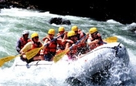 Group of people in helmets and life jackets in a raft on a whitewater river
